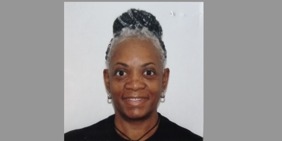 Professional headshot of a person with silver hair styled up, wearing black attire and silver earrings, with a warm genuine smile