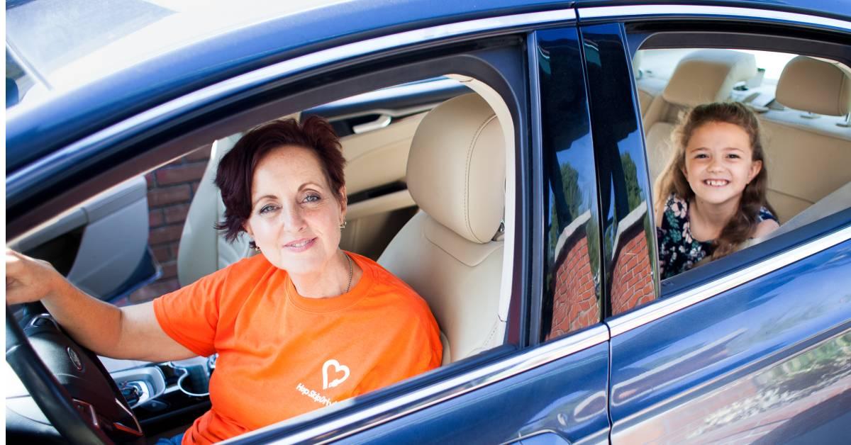 Driver in orange shirt and passenger in blue car with beige interior, showcasing professional ride service for families