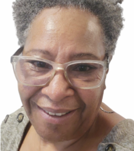 Close-up portrait of a person with silver hair wearing transparent frame glasses, showing a genuine warm smile