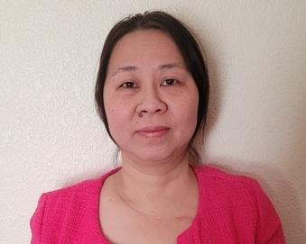 Professional headshot of a person wearing a bright pink sweater against a neutral background