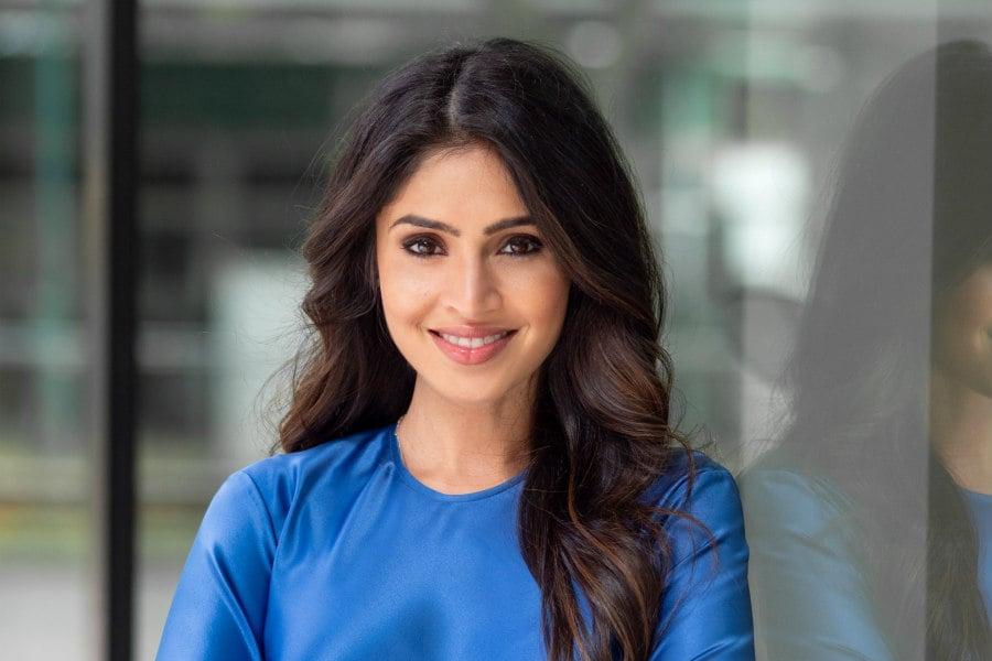 Professional woman wearing bright blue top smiling at camera in corporate setting with soft natural lighting