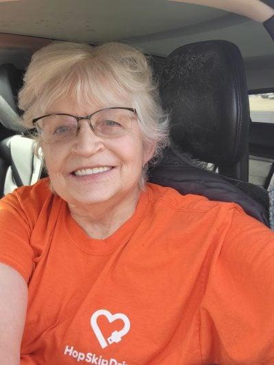 Senior volunteer wearing orange t-shirt with heart logo sitting in car