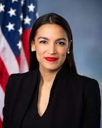 Professional portrait of a woman in a black blazer with red lipstick against an American flag backdrop