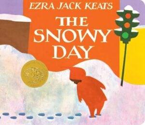 Book cover of 'The Snowy Day' by Ezra Jack Keats showing a red-coated figure in snow with a traffic light against an orange sky