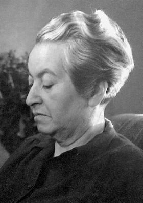 Black and white profile portrait of an elderly woman with short wavy hair wearing a dark garment, eyes closed in contemplation