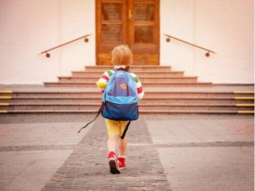Young child wearing backpack walking up to wooden doors at top of stairs